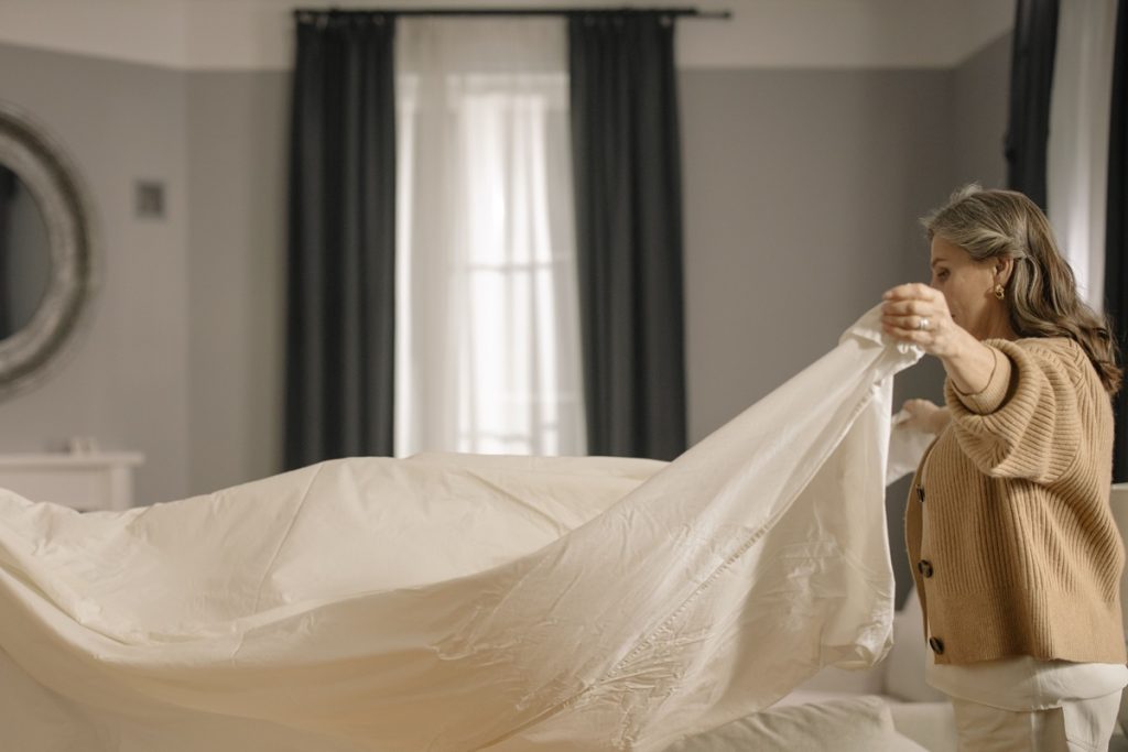 A woman changing bed sheets.