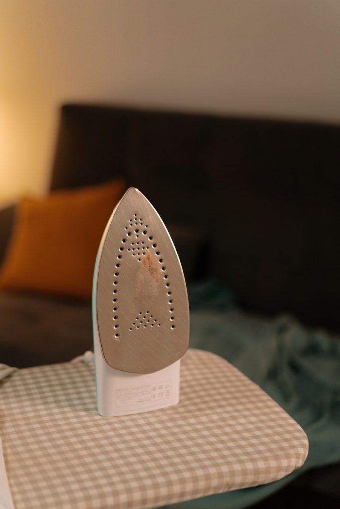 An iron standing on an ironing board.